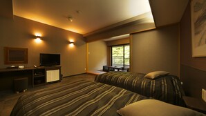 A hotel room with two beds, a desk with a TV, and a window providing a view of the outdoors.