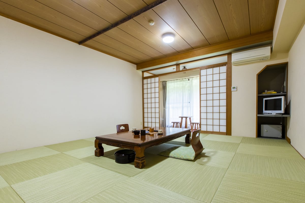 Ett traditionellt japanskt rum med tatamimattor på golvet, ett lågt träbord och skjutdörrar.