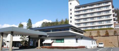 A multi-story hotel with a flat roof and a parking lot in front.