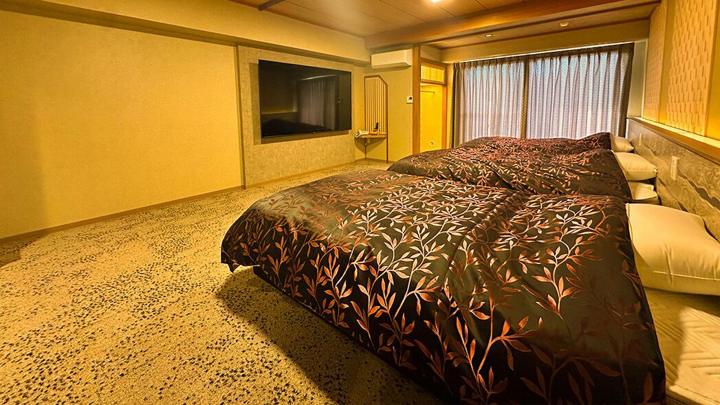 Een hotelkamer met een groot bed, een televisie en een raam met gordijnen.