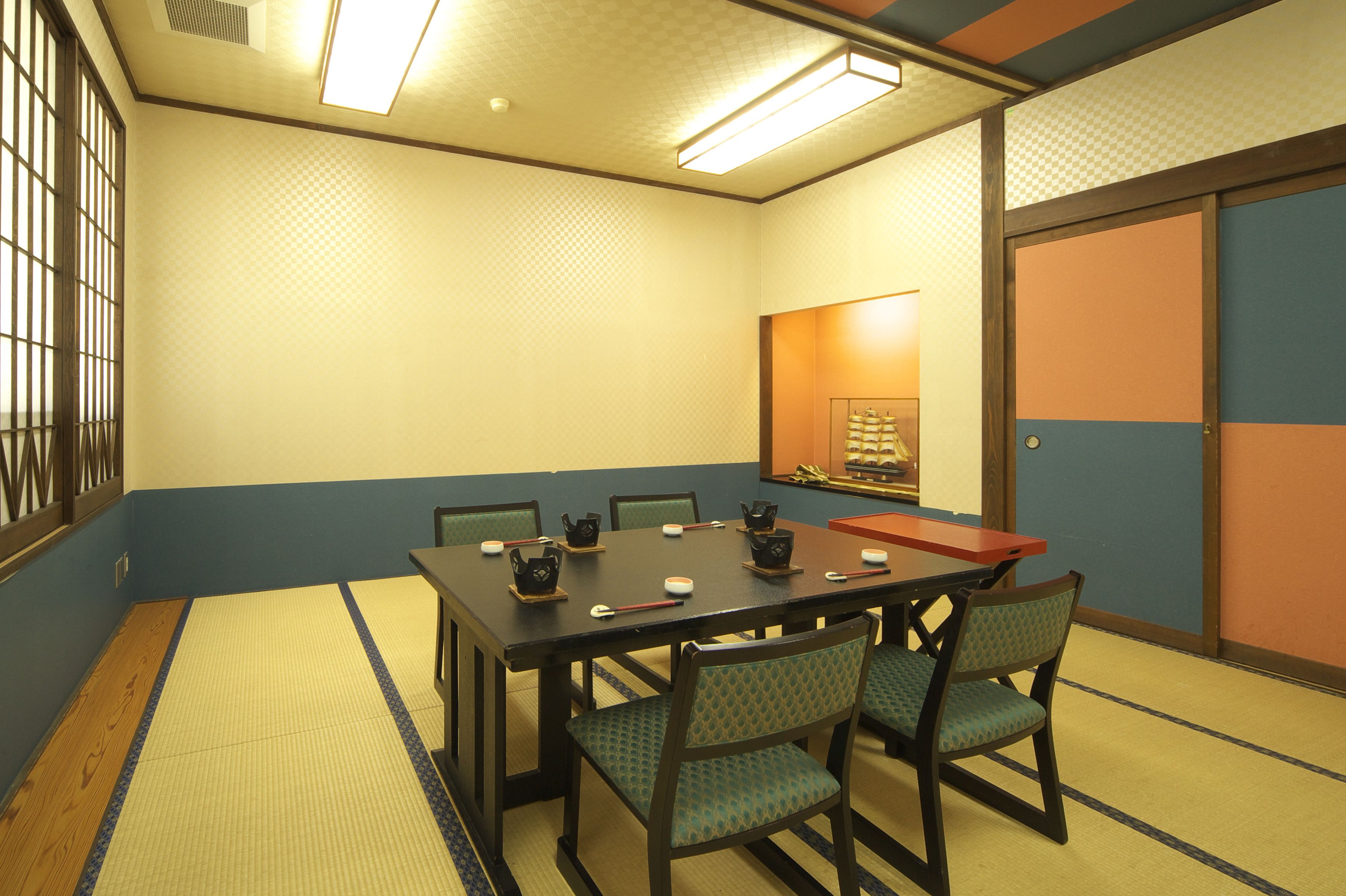 A traditional Japanese room with tatami flooring, a low table, and four chairs.