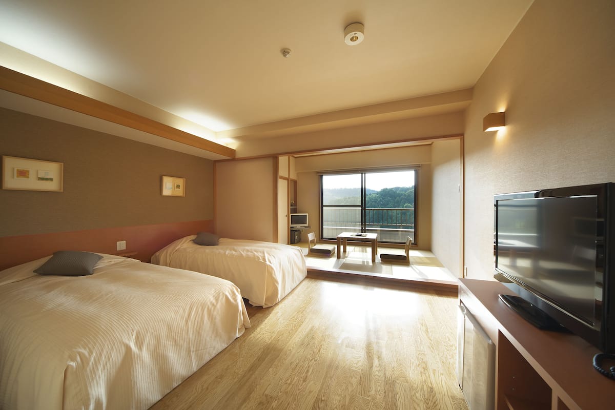 Ett hotellrum med två sängar, en TV, ett skrivbord och ett stort fönster med utsikt över omgivningarna.