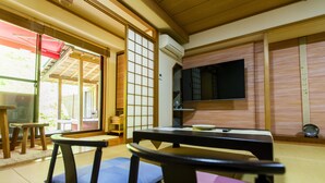 A traditional Japanese room with tatami mats, a low table, and a television.