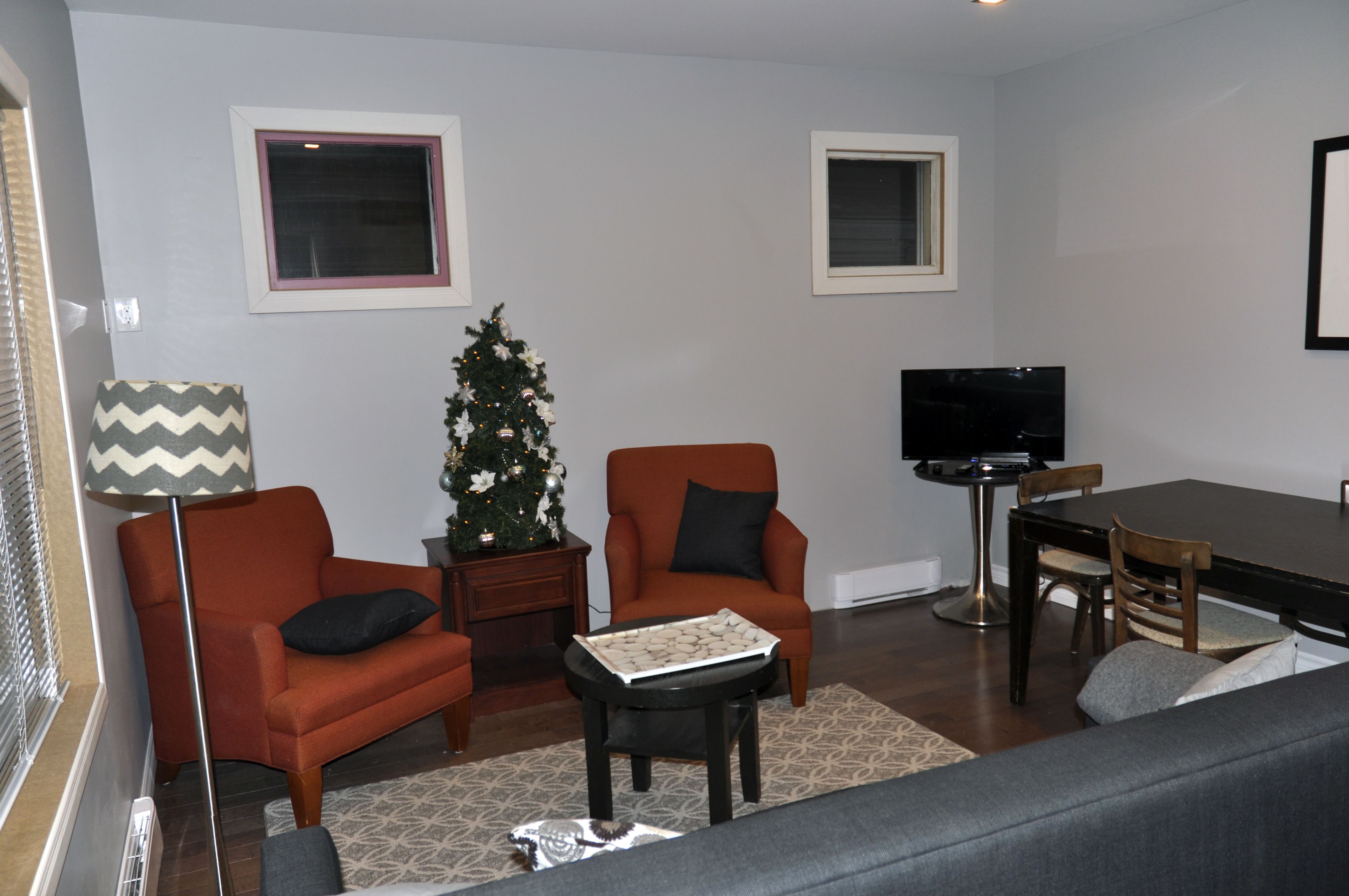Una sala de estar con sofá, dos sillones, una mesa de centro, televisor y un árbol de Navidad.