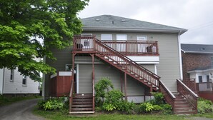 A two-story house with a wooden staircase leading to a balcony. - Moncton Suites - 267 Universite Ave (Moncton)
