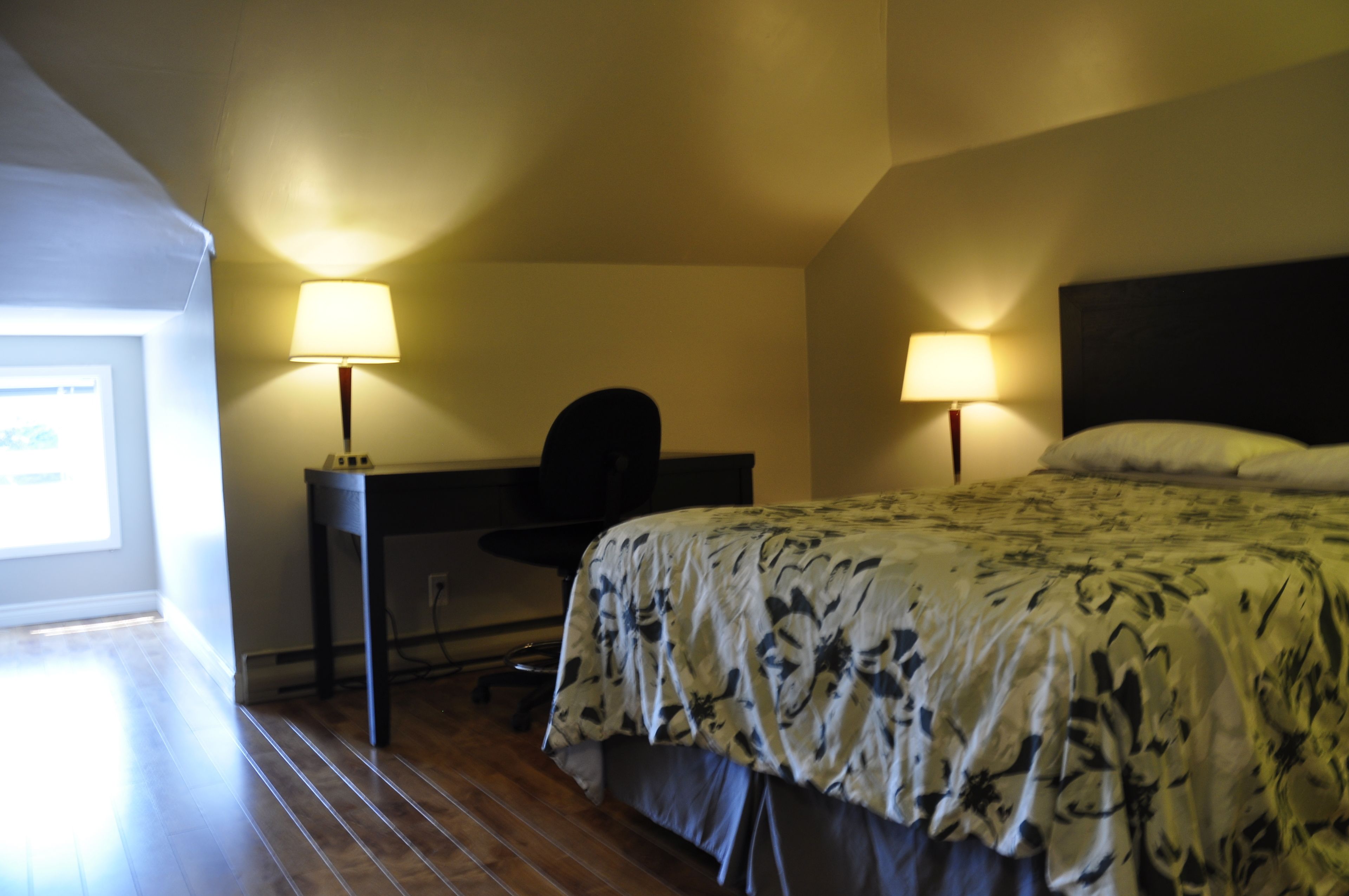 Een hotelkamer met een bed, bureau en twee lampen.