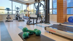 Een fitnessruimte met diverse trainingsapparaten, waaronder gewichten, een loopband en krachtapparaten.