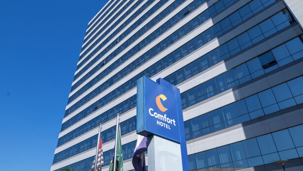 Een hoog hotelgebouw met een blauw bord waarop Comfort Hotel staat.