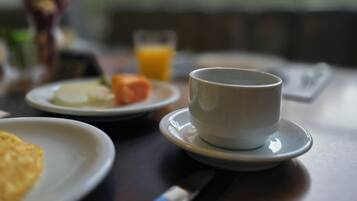 Una mesa de desayuno con una taza de café, un vaso de zumo de naranja y platos de comida.