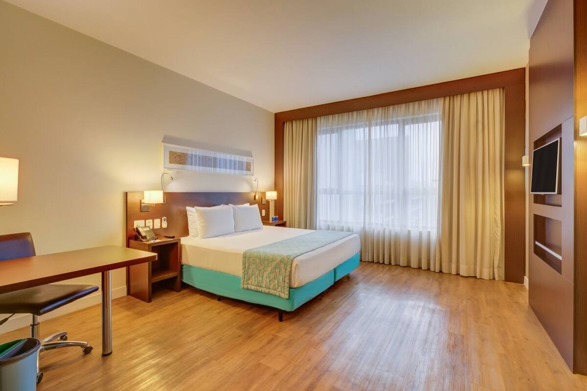 Een hotelkamer met een bed, nachtkastjes, een bureau en een stoel.