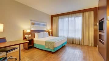 Ein Hotelzimmer mit Bett, Nachttischen, einem Schreibtisch und einem Sessel.