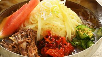 A bowl of food with noodles, meat, and vegetables.
