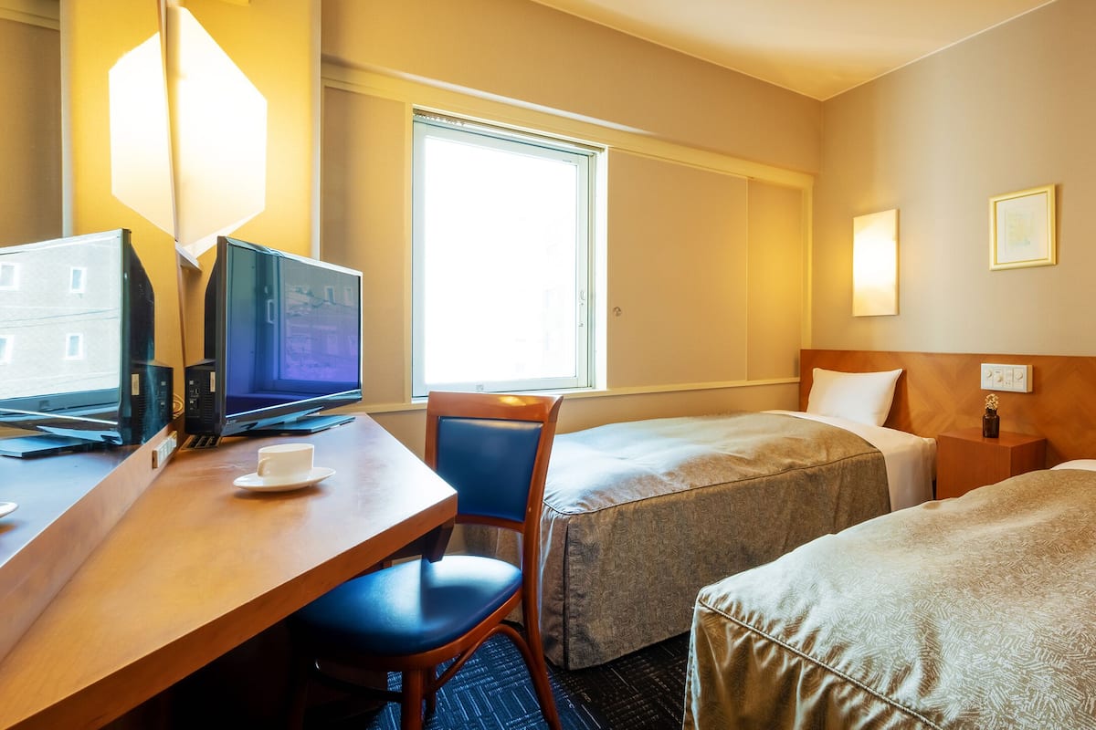 Habitación de hotel con escritorio, dos camas, una silla y televisión.