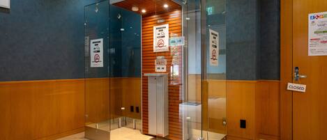 A modern elevator with glass doors, a wooden panel wall, and a closed door with a 'CLOSED' sign.
