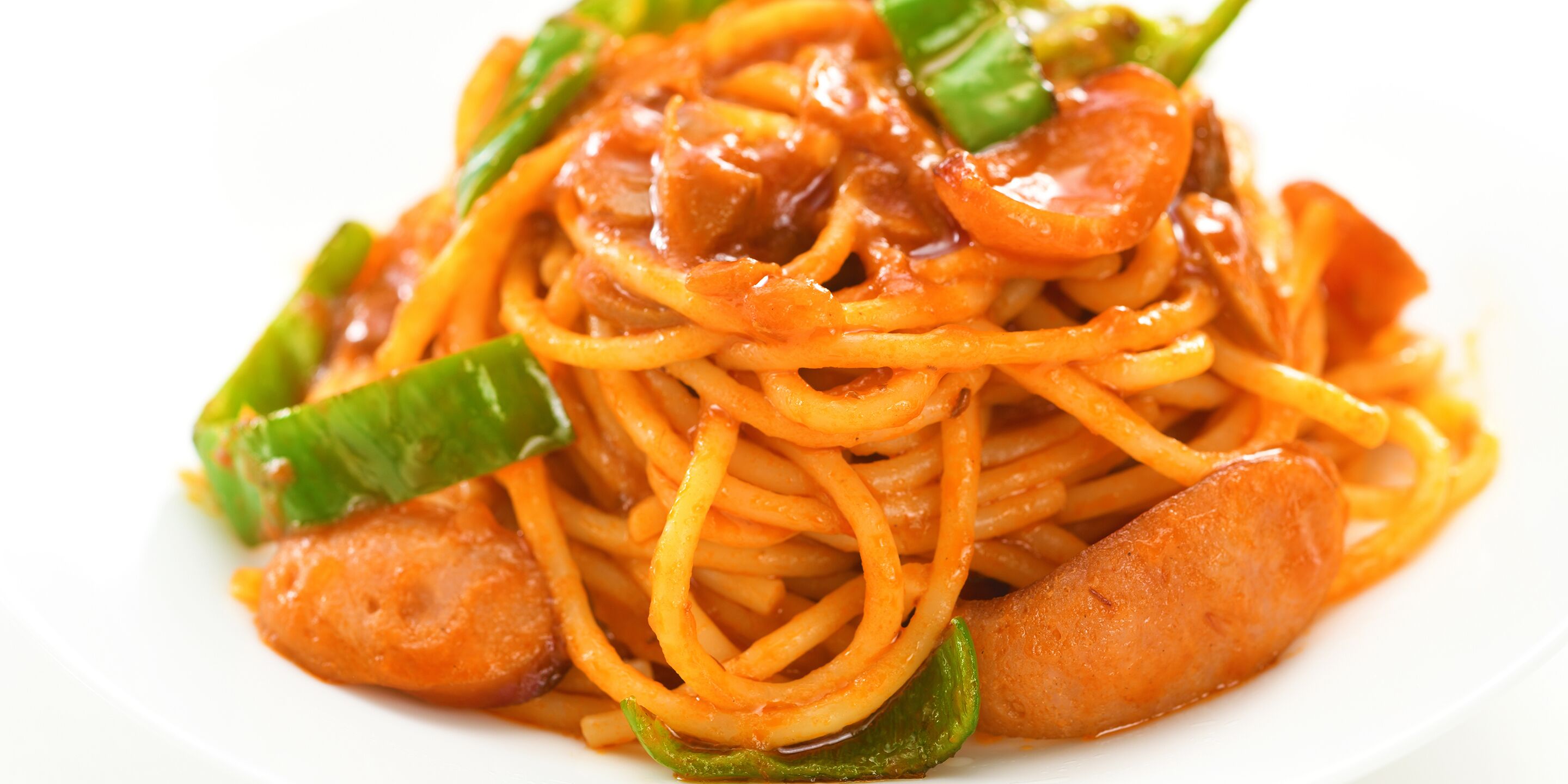 A plate of spaghetti with sausage and green bell peppers.