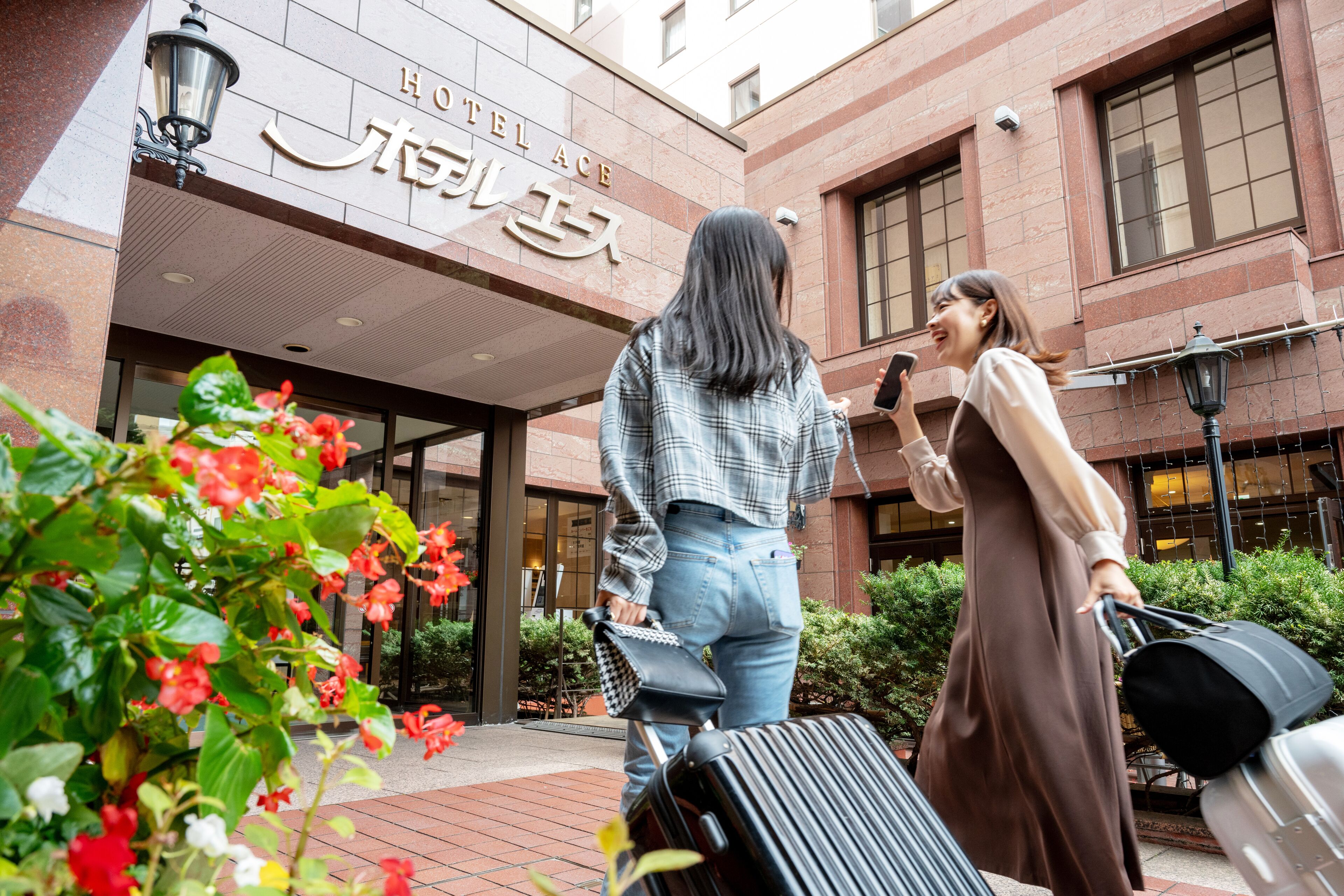 A hotel entrance with a sign reading "HOTEL ACE" and a person in a plaid shirt and jeans holding a suitcase.