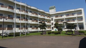 Un edificio de varios pisos con balcones, un estacionamiento y un cielo despejado.