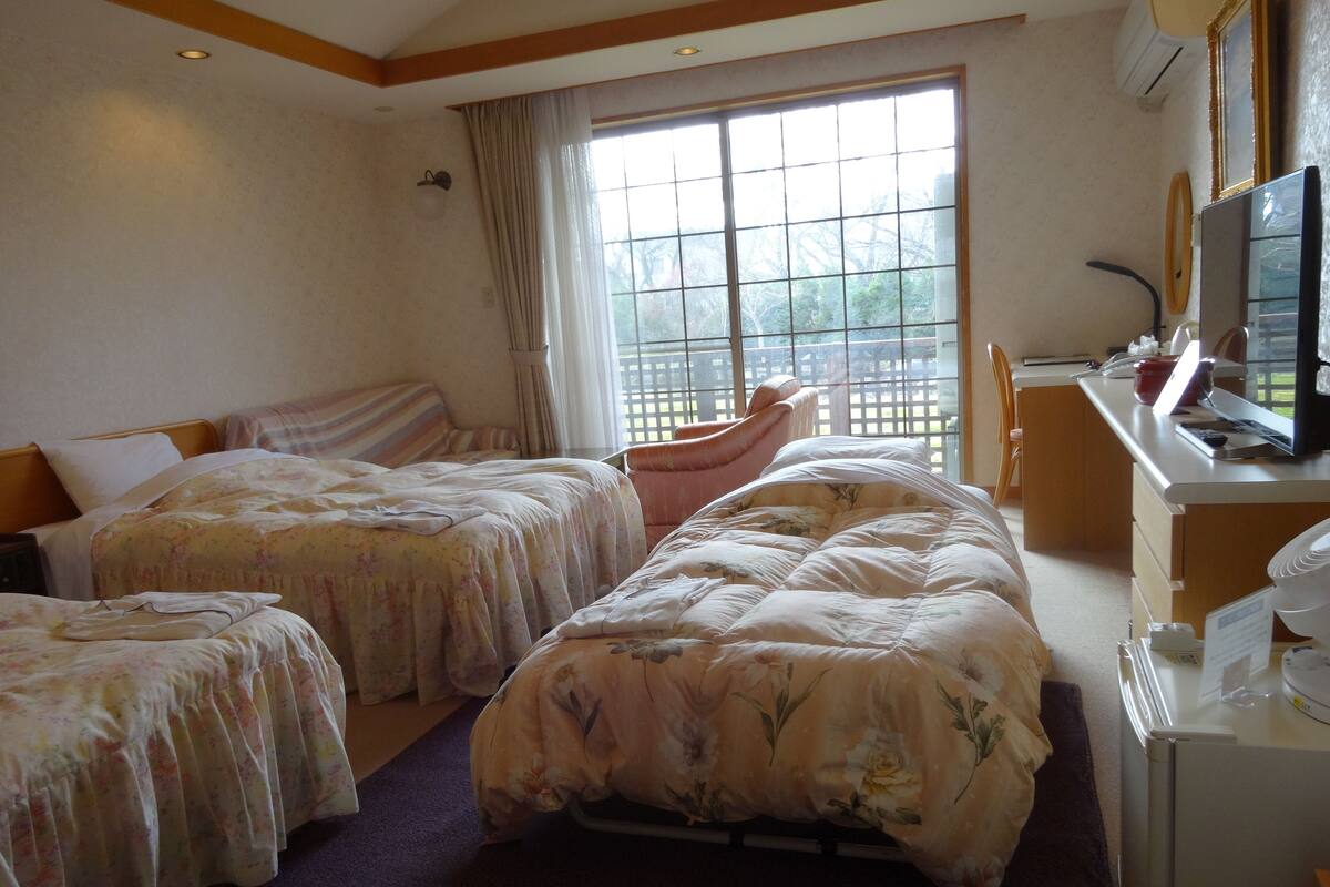 A hotel room with two beds, a desk, a chair, and a large window with a view.