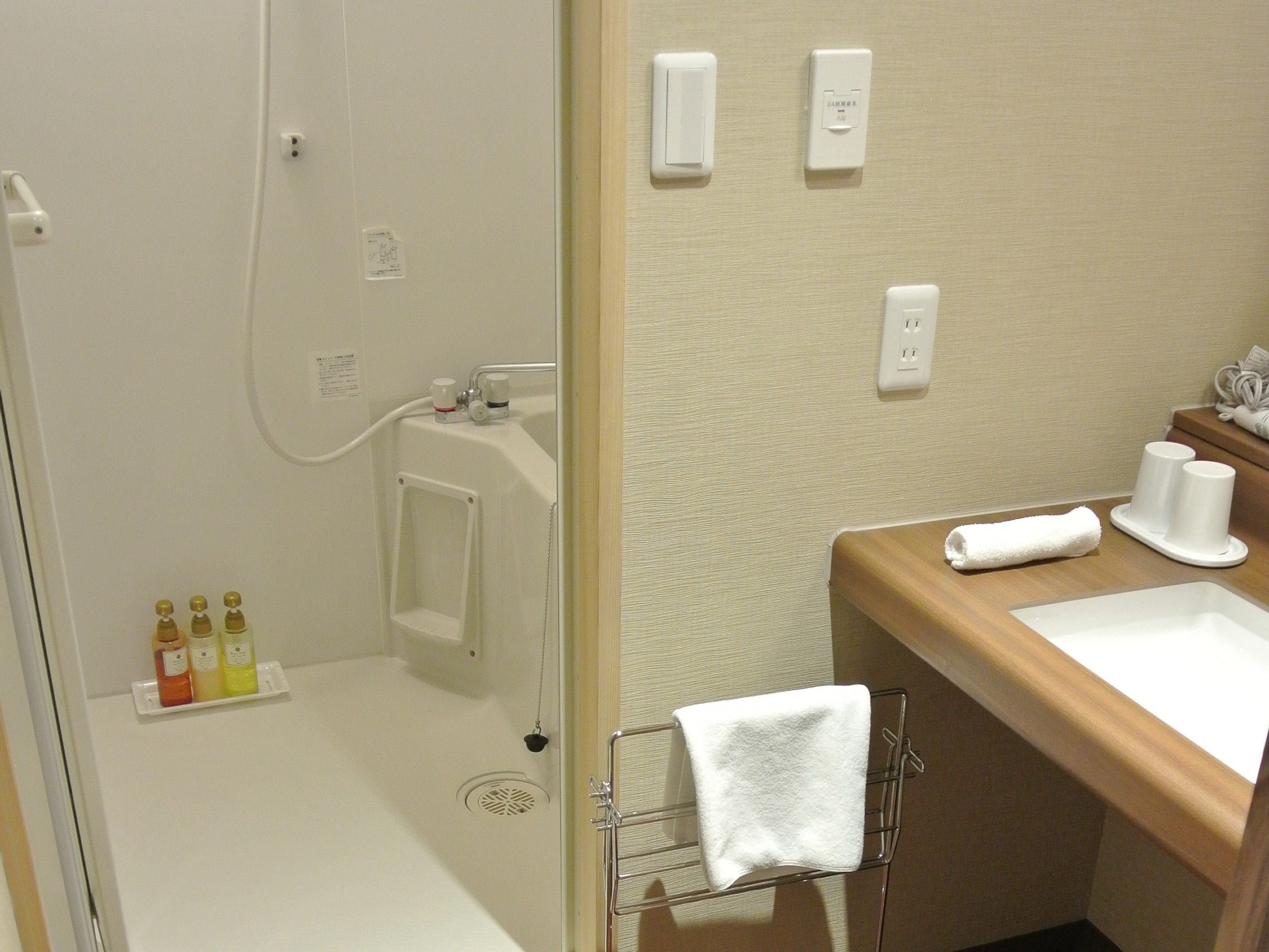 Un baño con ducha, lavamanos y artículos de aseo.