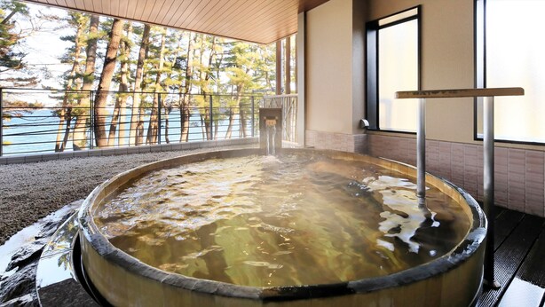 A hot tub with a view of trees and a body of water. - Hamabeno Ryouriyado Houraikan (Kamaishi)