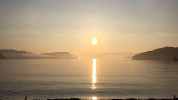 A sunrise over a calm body of water with distant landforms.