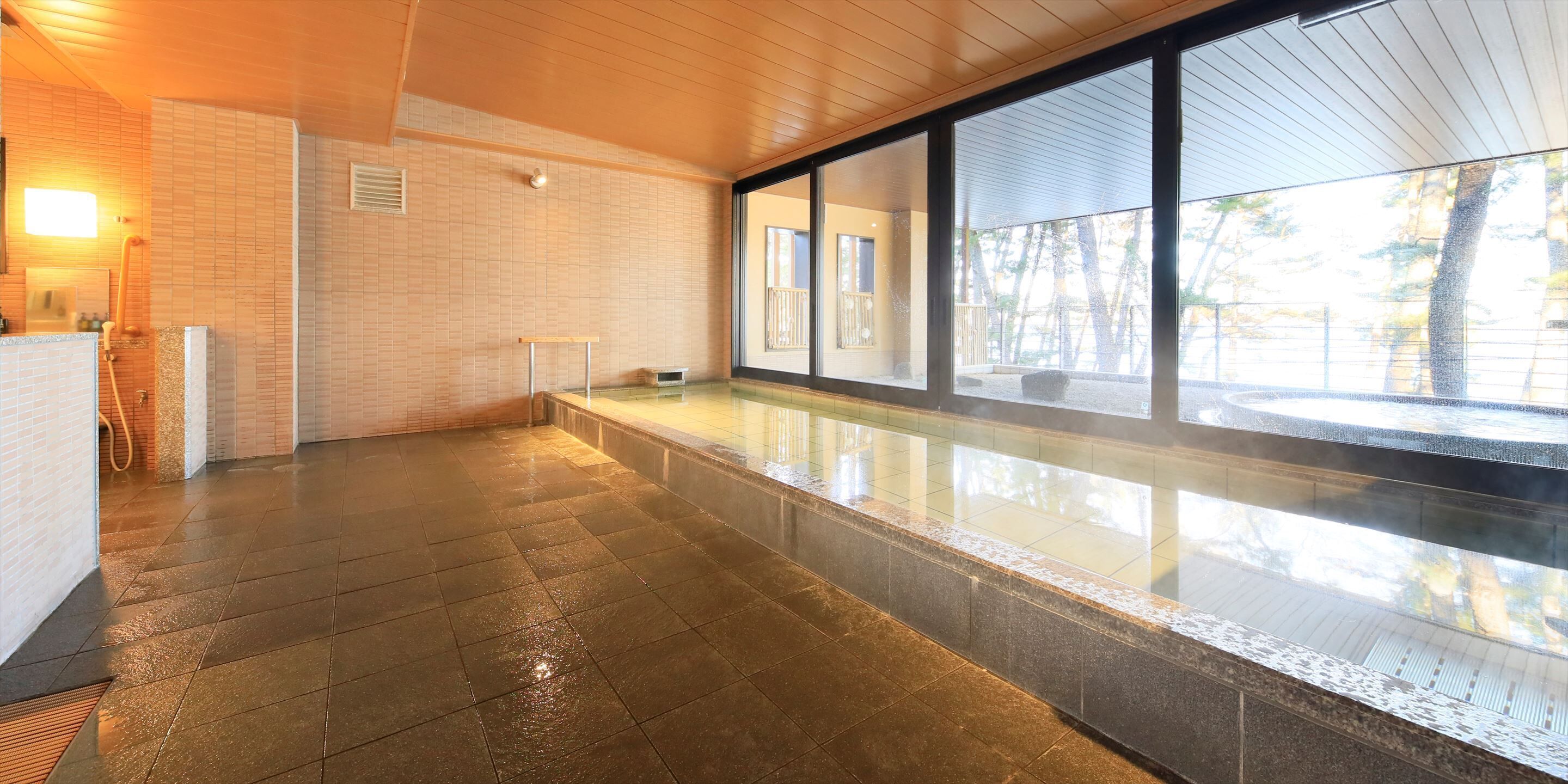 A modern indoor pool area with tiled flooring, a bench, and large windows offering views of the outdoors.