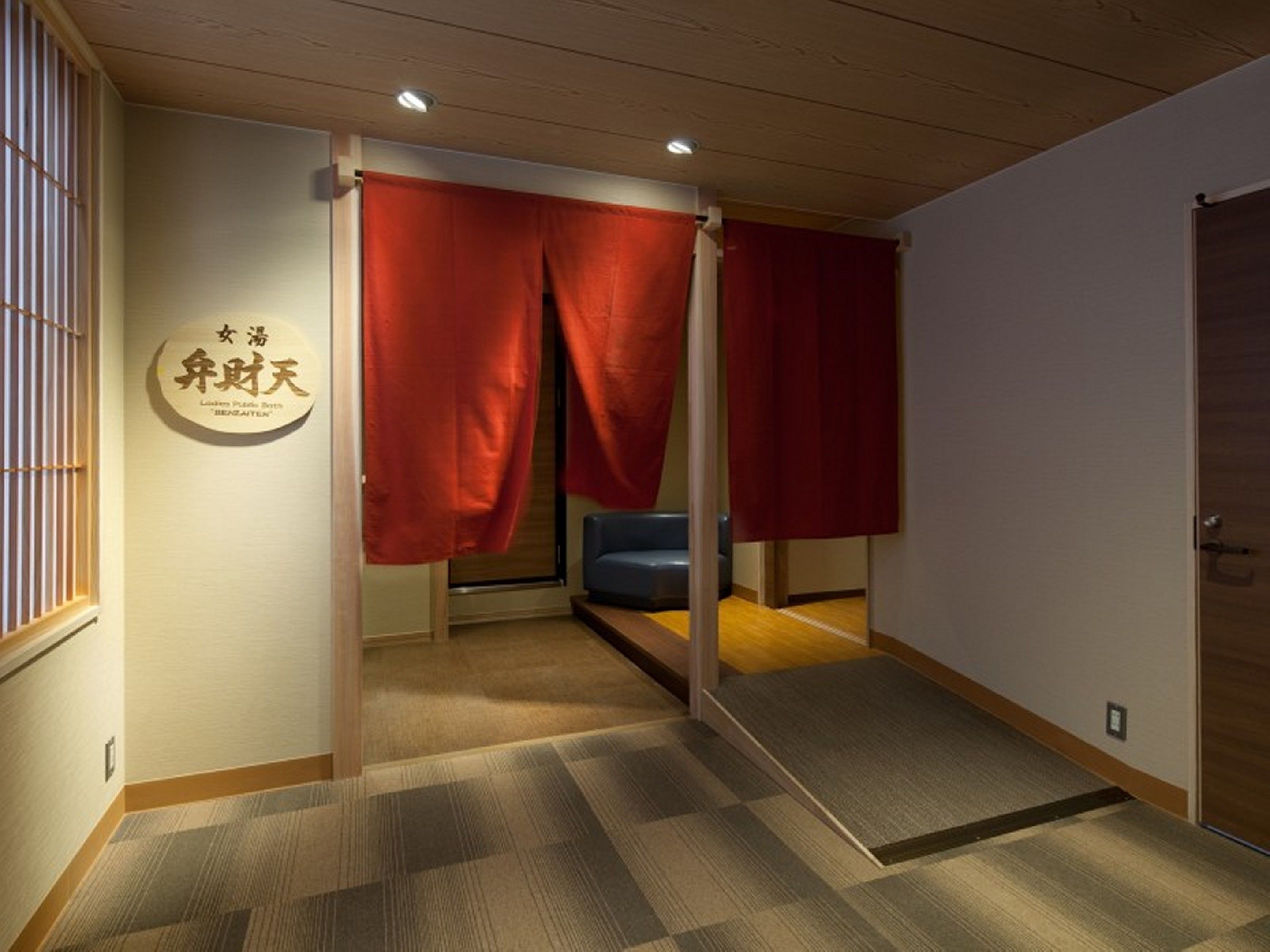 A room with tatami flooring, a blue sofa, and red sliding doors.