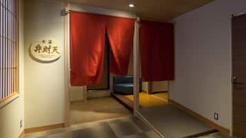 A room with tatami flooring, a blue sofa, and red sliding doors.