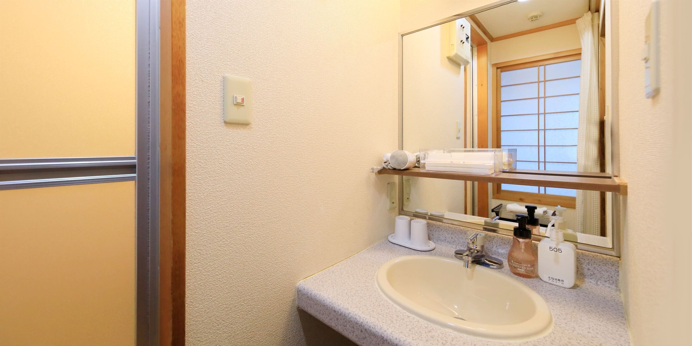 Une salle de bain équipée d’un lavabo, d’un miroir, d’un porte-serviettes et d’articles de toilette.