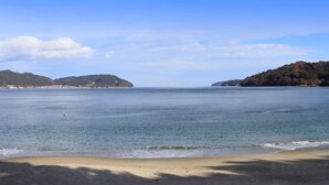 A beach with calm waters, sandy shore, and forested hills in the background. - Hamabeno Ryouriyado Houraikan (Kamaishi)