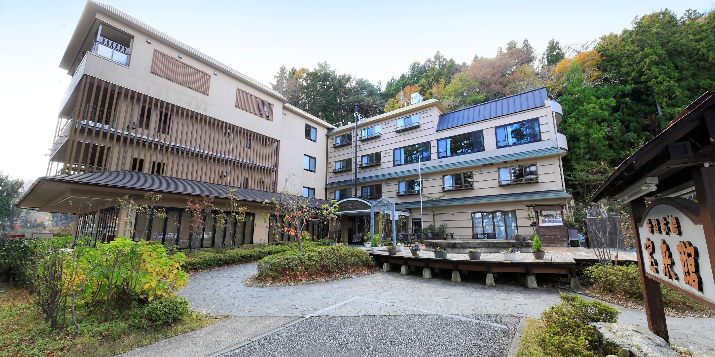 Un hotel de varios pisos con un diseño arquitectónico moderno, con balcones y un patio ajardinado.