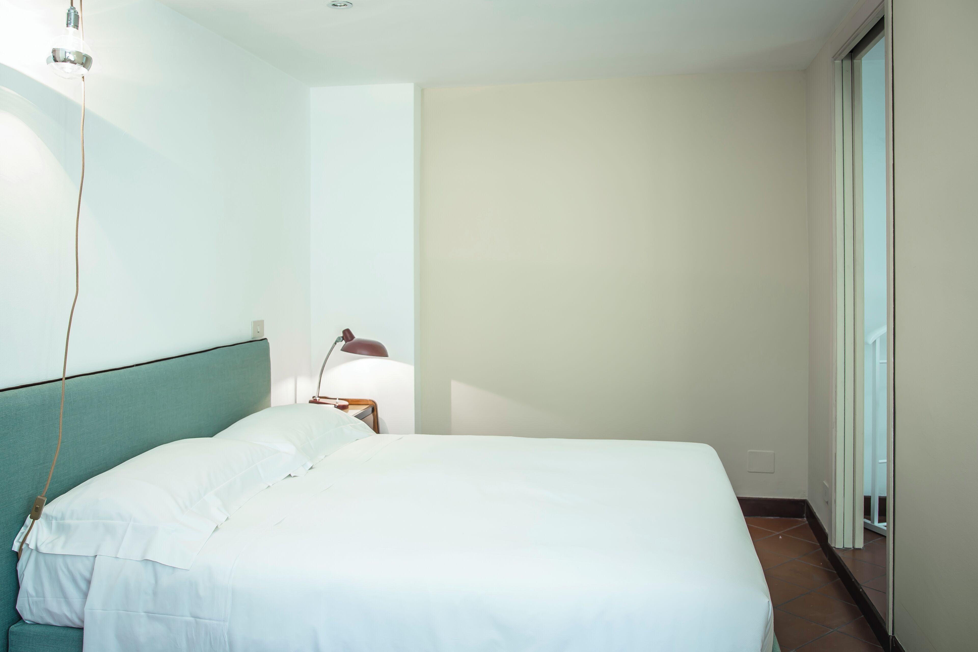 Habitación de hotel con una cama grande, una lámpara de noche y vistas a una puerta corredera.