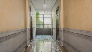 A hallway with a marble floor, a ceiling light, and a door with frosted glass panels. - Brera Apartments in Porta Romana (Milan)
