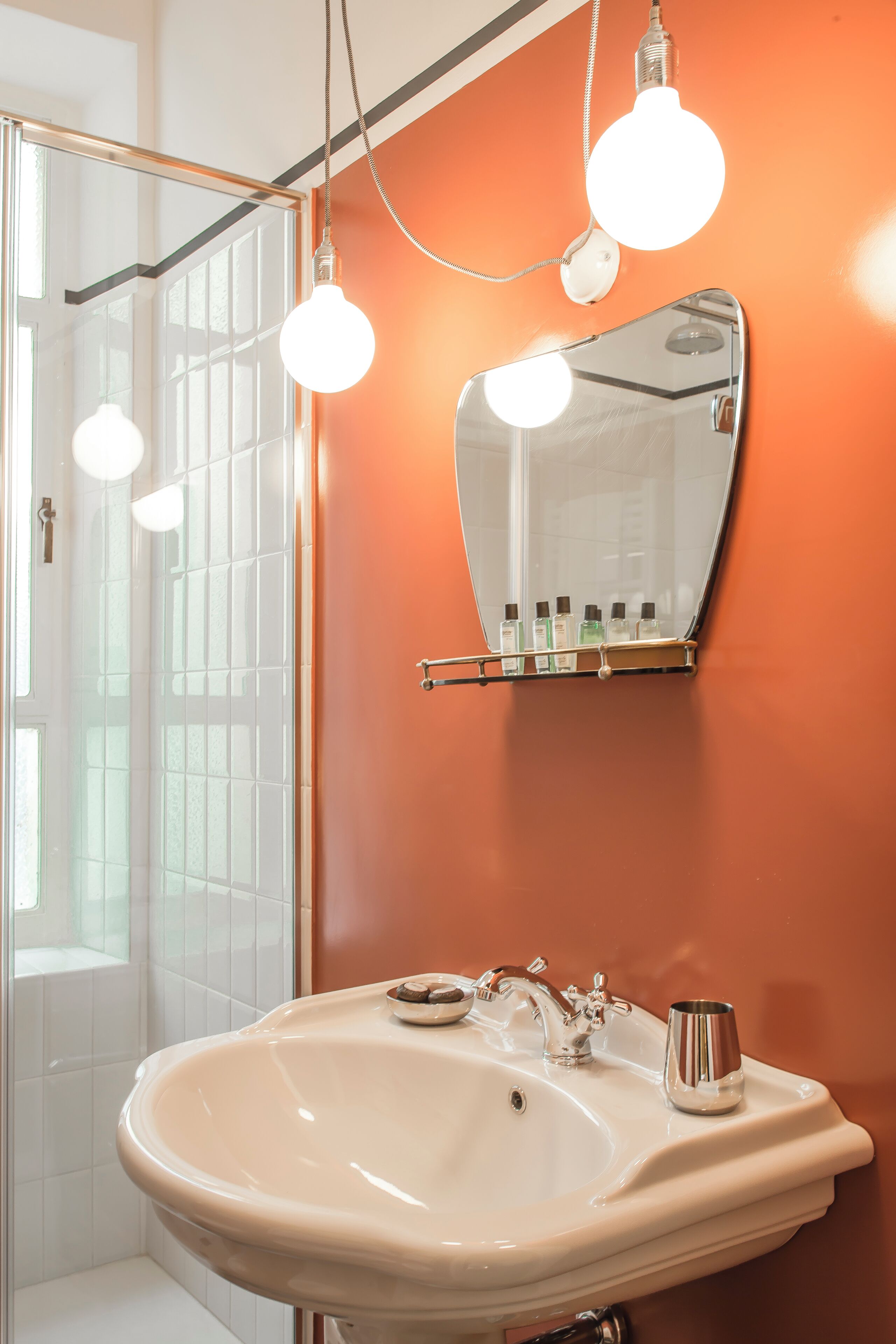 Un baño con lavamanos blanco, un espejo y una puerta de ducha.