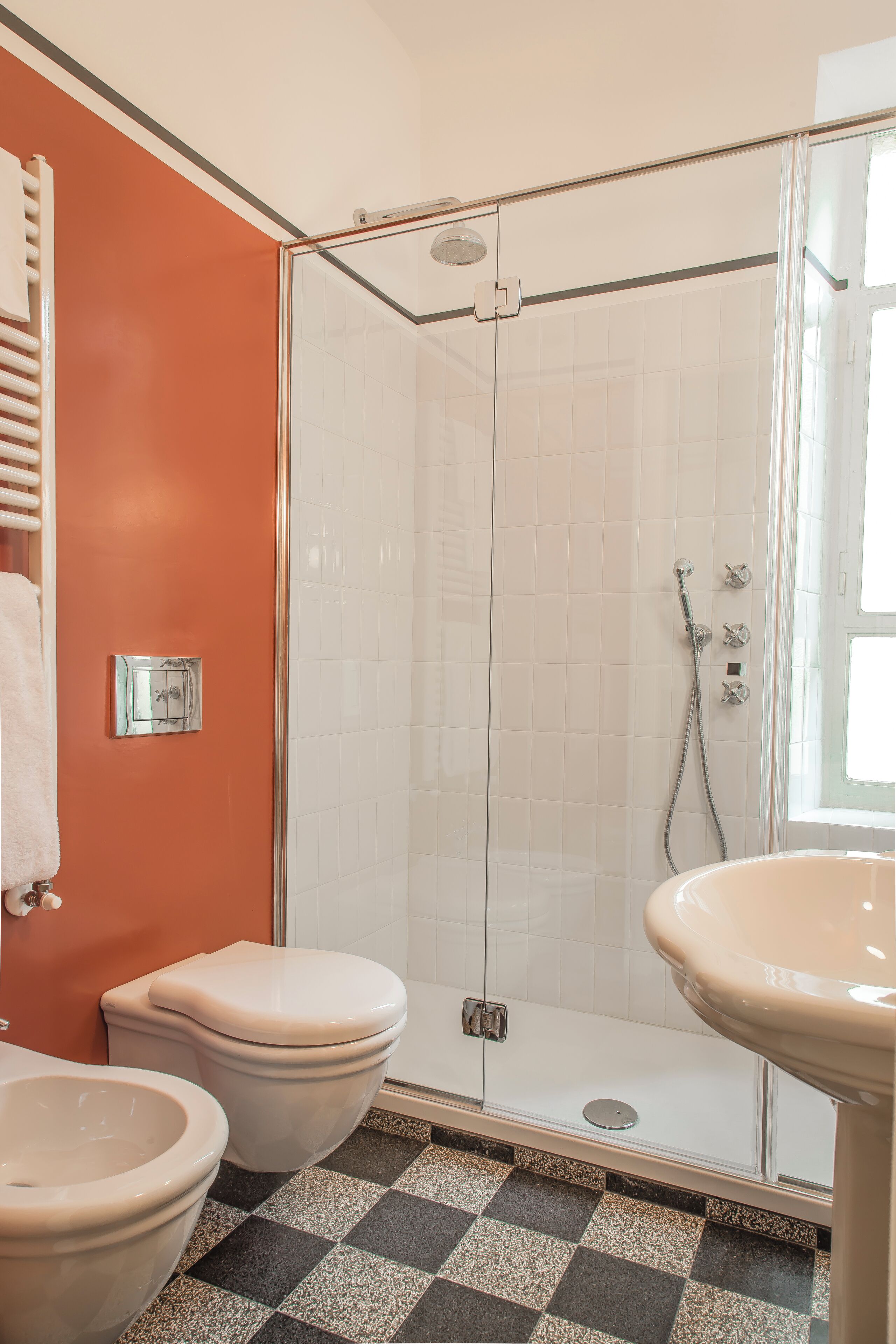 Une salle de bain avec une douche à parois de verre, deux toilettes et un lavabo.