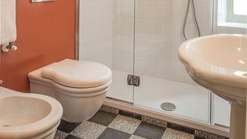 Une salle de bain avec une douche à parois de verre, deux toilettes et un lavabo.