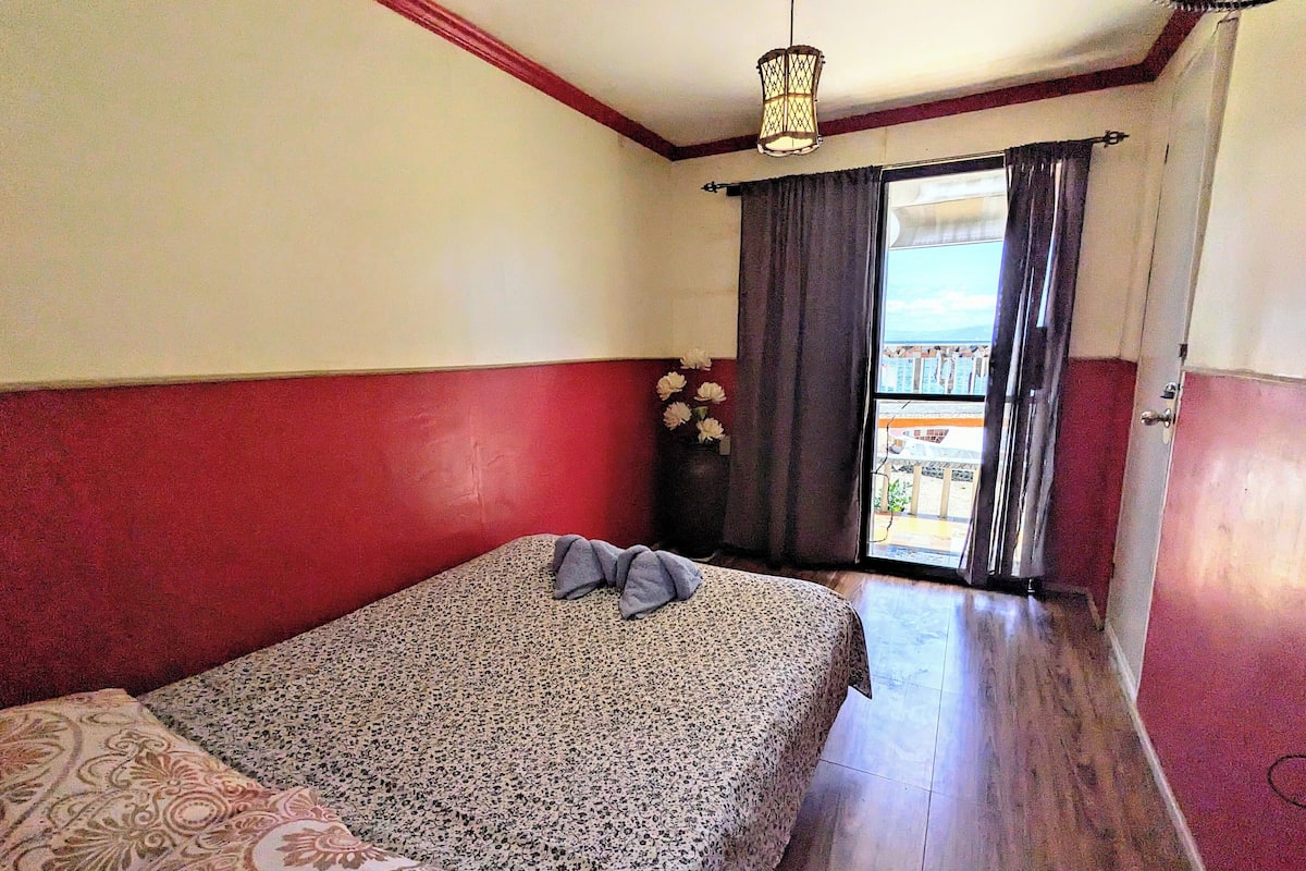 Une chambre avec un lit, une fenêtre avec des rideaux et une vue sur l’extérieur.