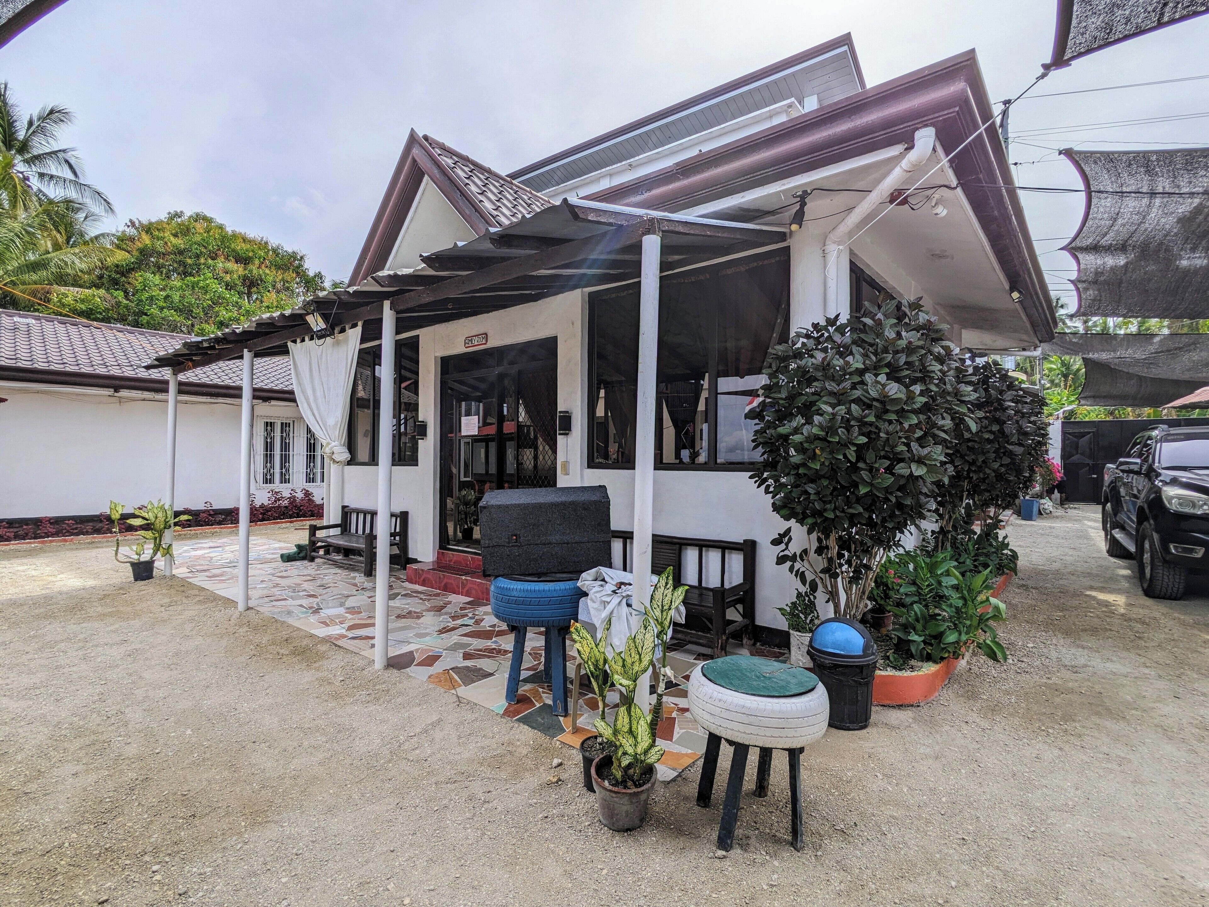 A house with a covered porch, a small outdoor seating area, and several potted plants.