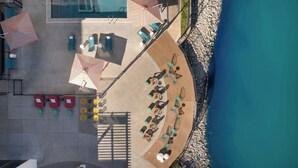 An aerial view of a poolside area with sun loungers, umbrellas, and a wooden deck. - Aloft by Marriott Wichita (Wichita)