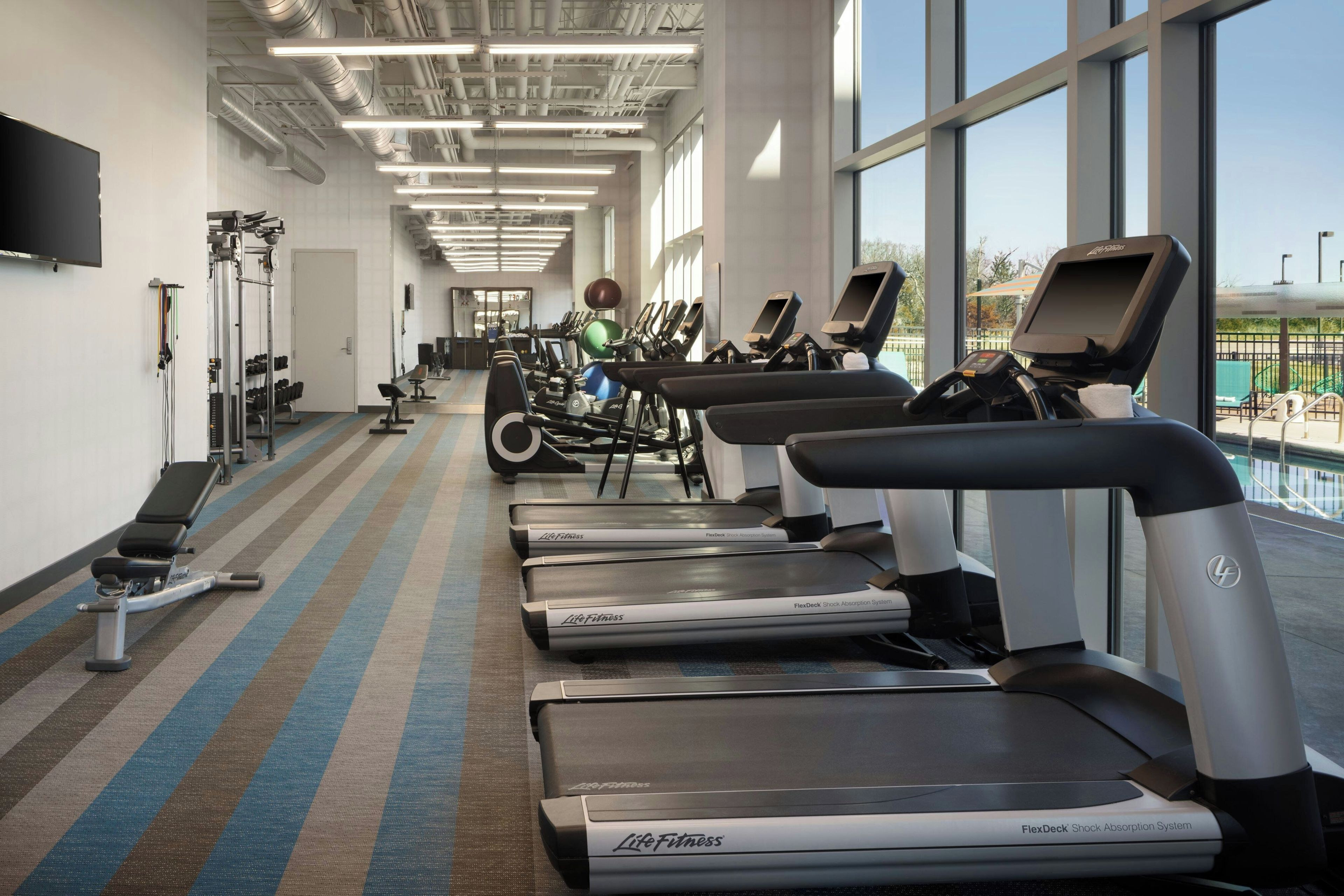 A gym with treadmills, weight machines, and a large mirror.