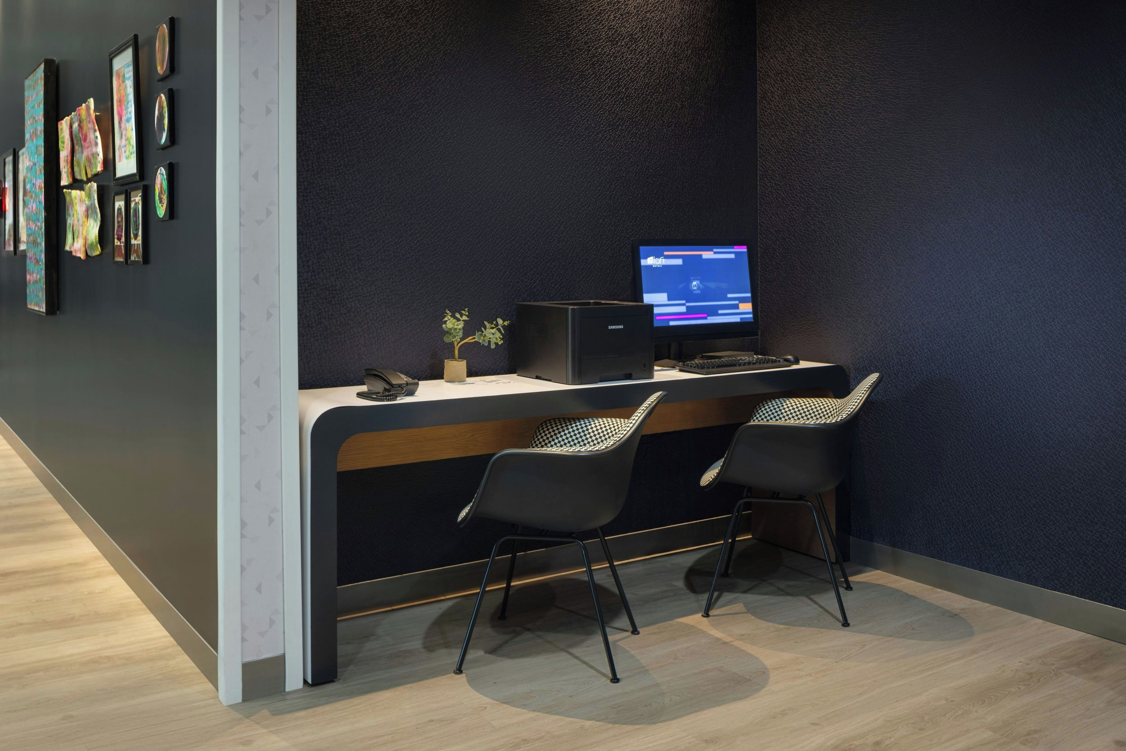 A modern reception desk with two black chairs, a computer monitor, and a phone.
