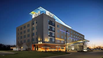 A modern hotel with a flat roof, multiple floors, and a covered entrance area.