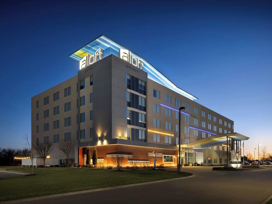 Um hotel moderno com telhado plano, vários andares e área de entrada coberta.