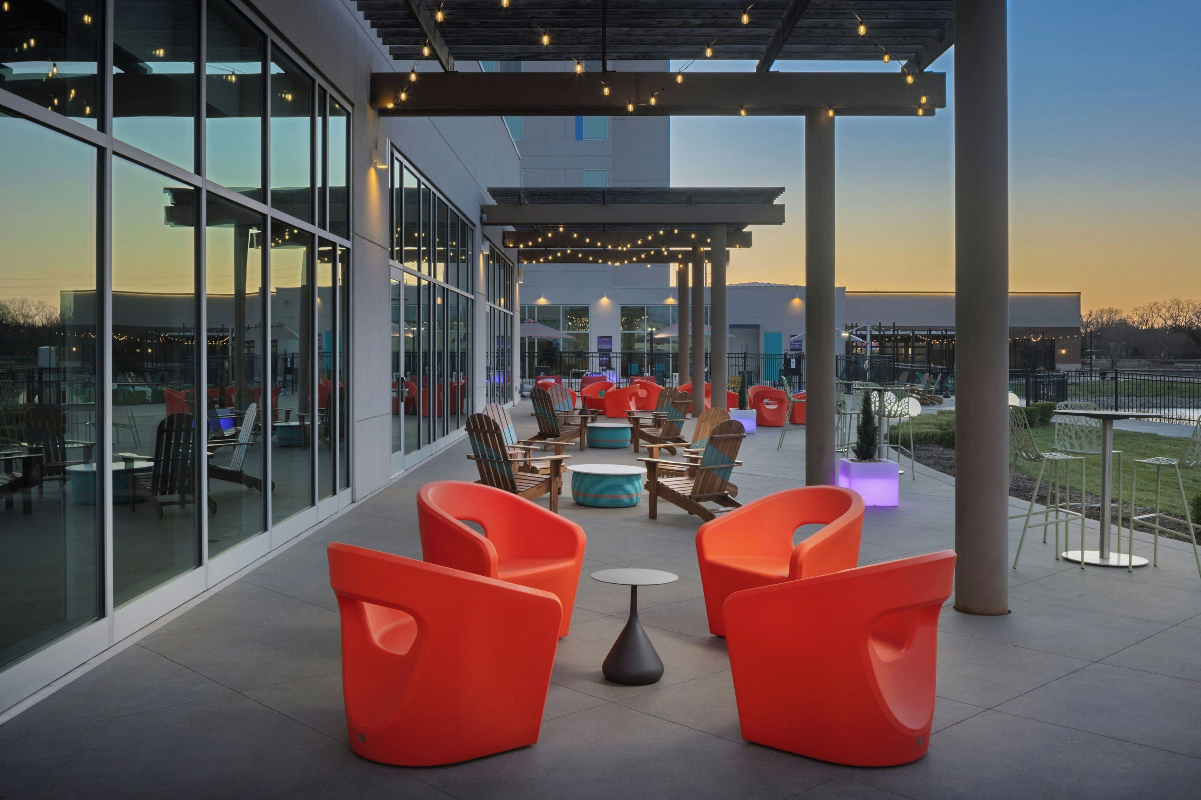 An outdoor seating area with modern chairs and tables, large windows, and a view of the surrounding area.