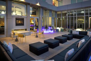 Un espacio moderno al aire libre con sofás y sillones, una chimenea y ventanas amplias.