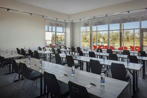 A conference room with multiple tables and chairs, large windows, and a view of an outdoor playground. - Aloft by Marriott Wichita (Wichita)