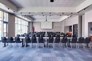 A conference room with rows of chairs, a projector screen, and flags. - Aloft by Marriott Wichita (Wichita)
