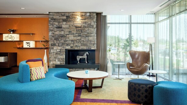 Una sala de estar moderna con chimenea de piedra, sofás azules y un ventanal con vistas a la ciudad.
