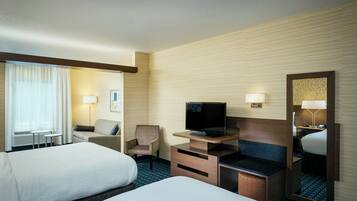 Habitación de hotel con dos camas, televisión, escritorio y silla.