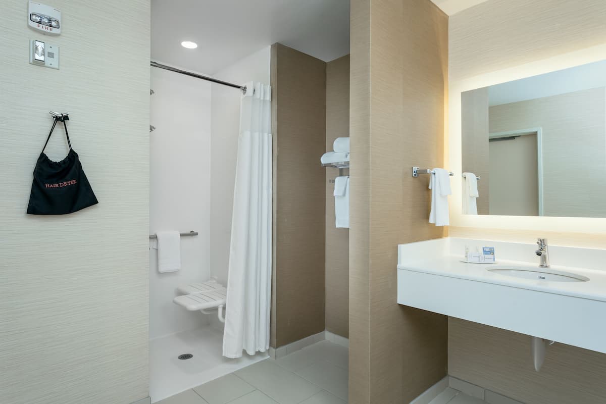 A modern bathroom with a white sink, mirror, and shower curtain.